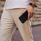 Man carrying Midnight Black Evolve Smart Wallet in right hand, dressed in cream linen pants