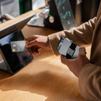 Steel Blue Evolve Smart Wallet being handed across café table in warm lighting