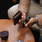Midnight Black Evolve wallet and Vault Key Case on café table