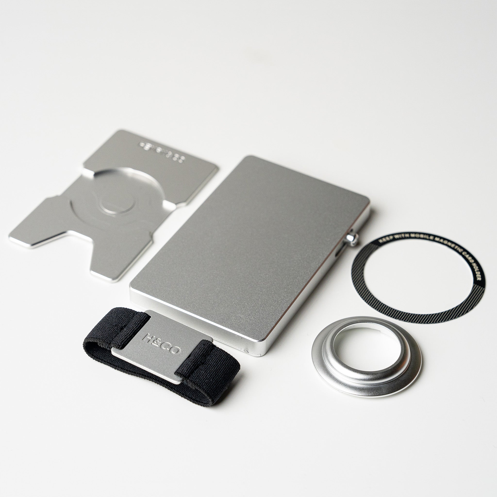 Platinum wallet with airtag holder, backplate, band and magnetic ring laid flat in bundle configuration