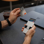 Hand inserting credit card into Platinum Evolve Smart Wallet at a desk setup