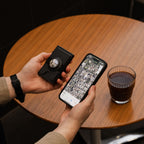 Midnight Black wallet with airtag and on café table with phone and coffee