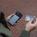 Hands inserting card into Steel Blue Evolve Smart Wallet on red brick path