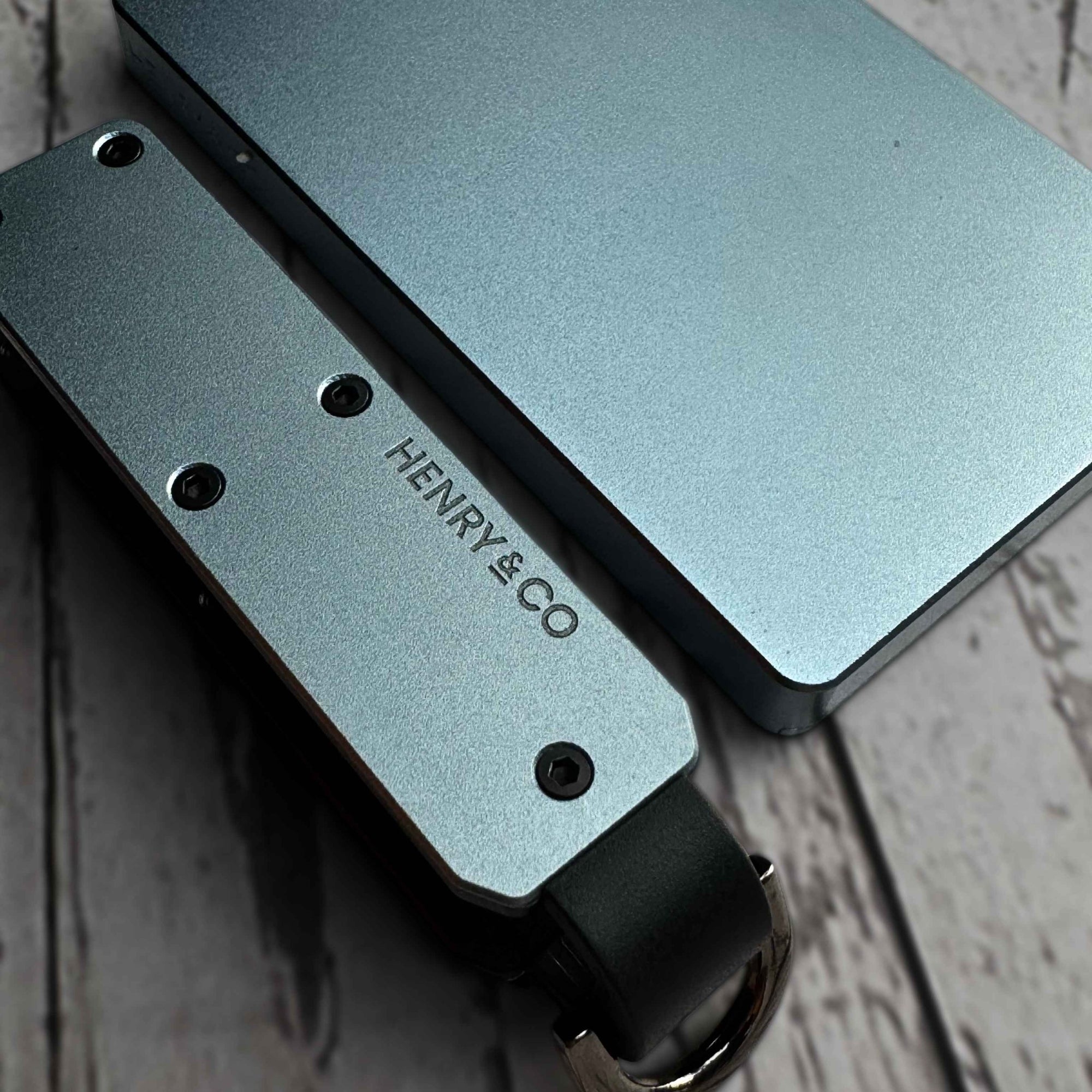 Close-up detail of Vault Key Case in Steel Blue resting beside Evolve Smart Wallet