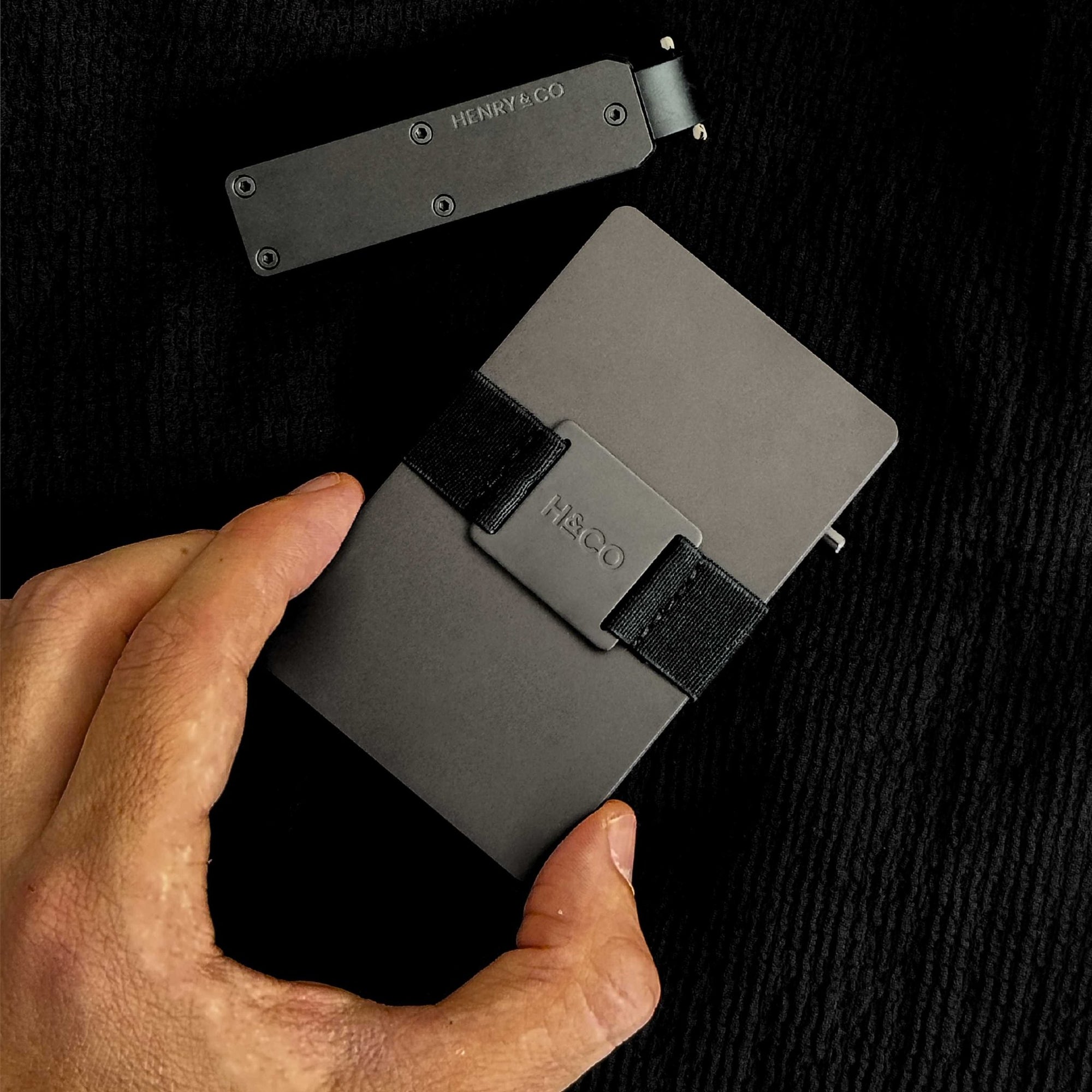 Hand grabbing Vault Key Case and Evolve Smart Wallet in Midnight Black with band